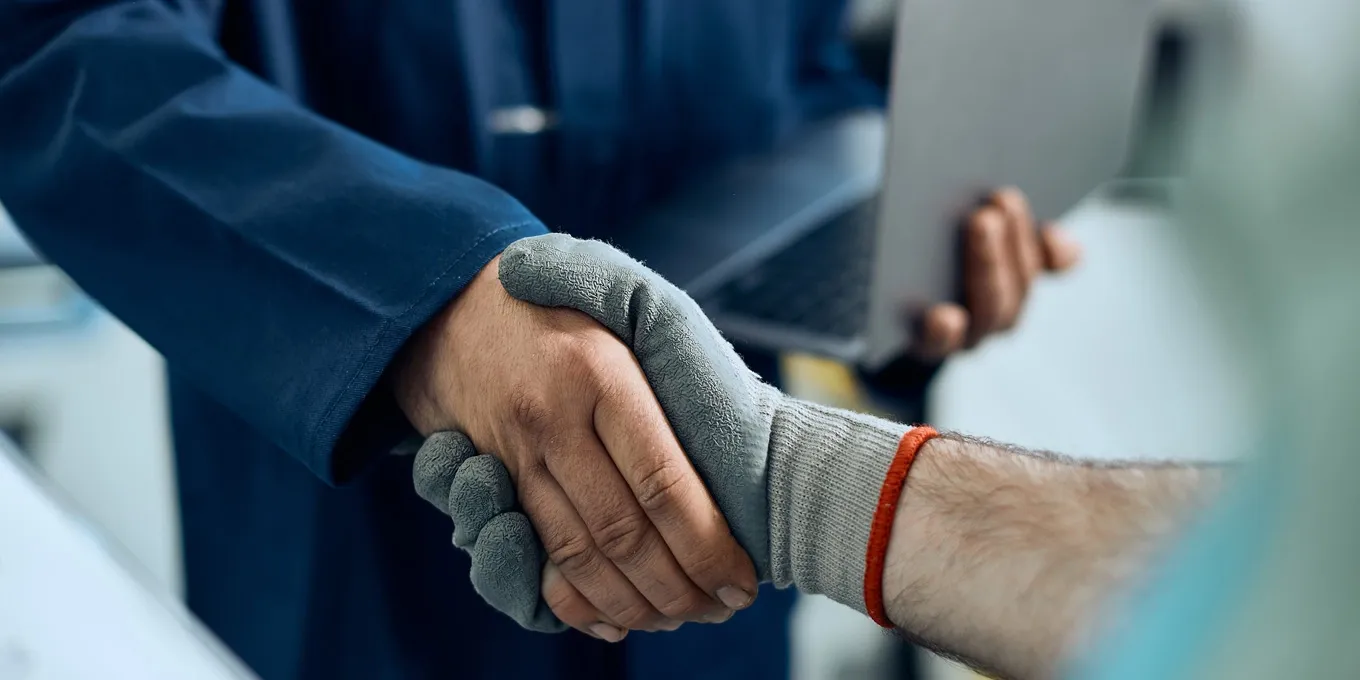 Zwei Personen geben sich neben einem Fahrzeug die Hand