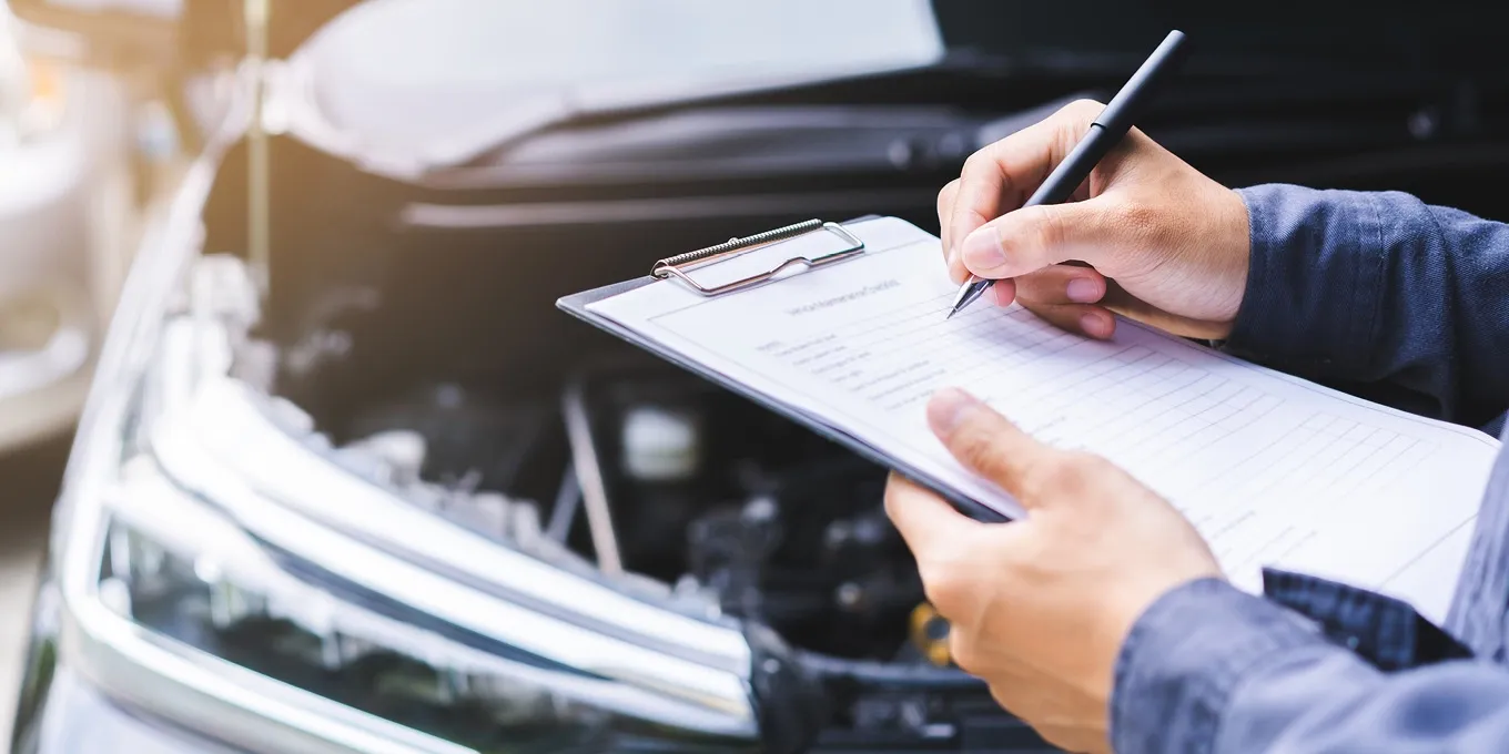 Person notiert Angaben auf einem Klemmbrett vor einem Auto