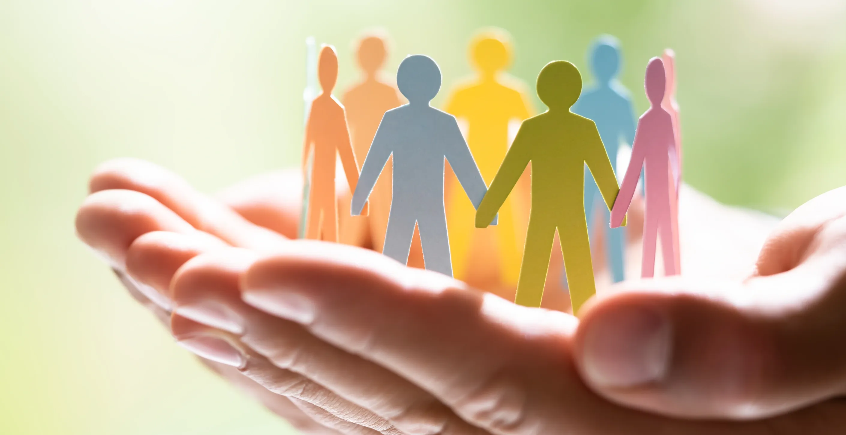 Bunte stilisierte Personenfiguren stehen auf einer geöffneten Hand und symbolisieren Vielfalt und Gemeinschaft