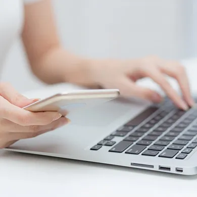 Person nutzt Laptop und Smartphone
