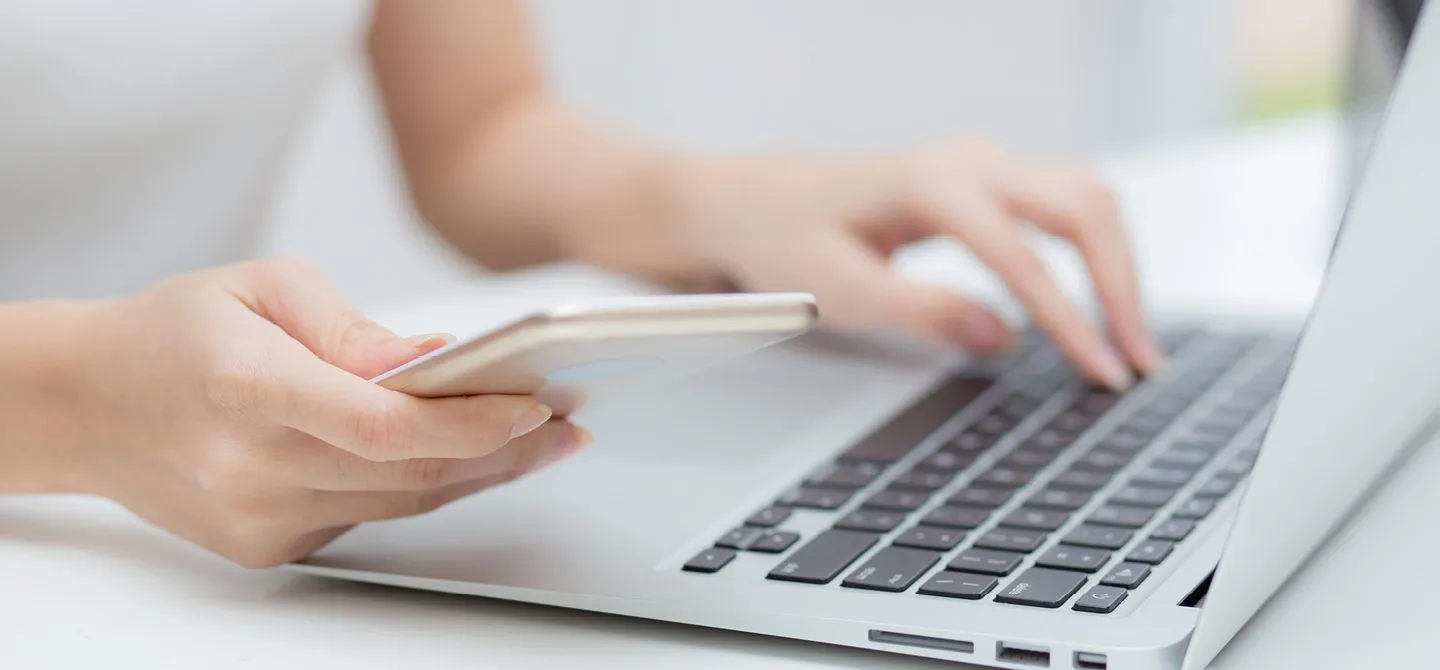 Person nutzt Laptop und Smartphone