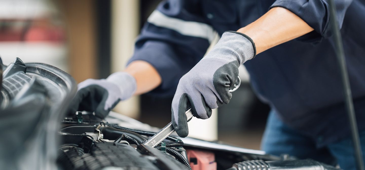 Kfz-Mechaniker bei Wartungsarbeiten im Motorraum eines Fahrzeugs