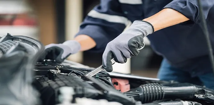 Kfz-Mechaniker bei Wartungsarbeiten im Motorraum eines Fahrzeugs